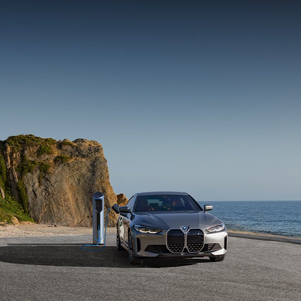 Charging BMW i4 parked in coastal landscape
