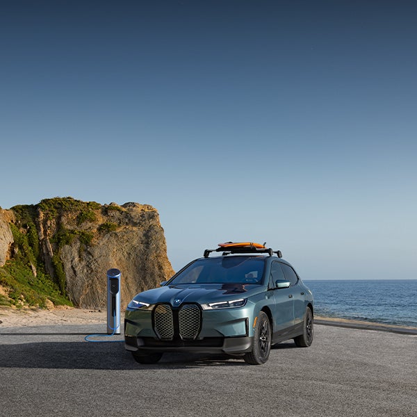Charging BMW iX parked in coastal landscape
